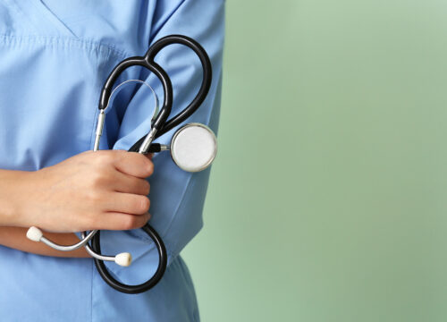 Photo of a nurse's scrubs, hand, and stethoscope